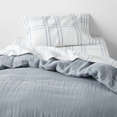 an unmade bed with blue sheets and pillows