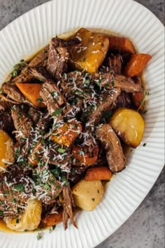 a white plate topped with meat and potatoes