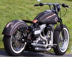 a black motorcycle parked on the side of a road next to green grass and trees