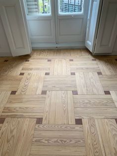 an empty room with wood flooring and two windows