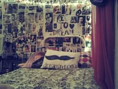 a bed room with a neatly made bed and lots of pictures on the wall behind it