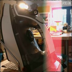 a black and white iron sitting on top of a table next to a red light