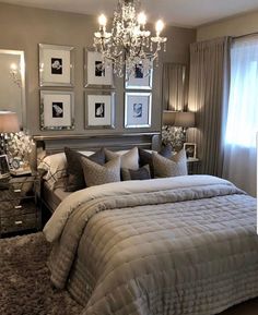 a bedroom with a large bed, chandelier and pictures on the wall above it