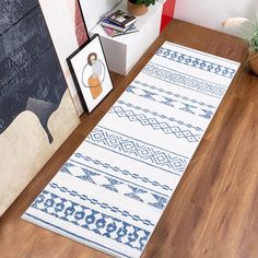 a white and blue rug sitting on top of a wooden floor next to a potted plant