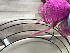 a close up of a bowl with some wire wrapped around it and flowers in the background