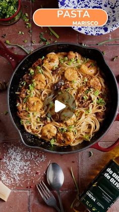 pasta with shrimp and parsley in a skillet next to other cooking utensils