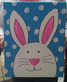 a painting of a rabbit with polka dots on it's face is shown in front of a woman