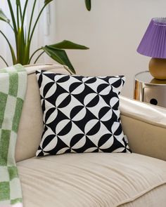 a black and white pillow sitting on top of a couch next to a purple lamp