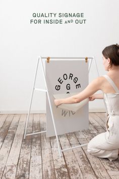 a woman sitting on the floor next to an easel with writing written on it