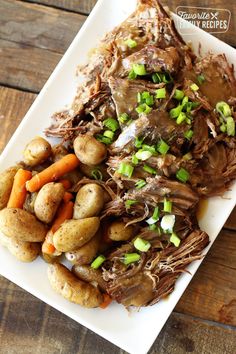 a white plate topped with roast beef and veggies on top of a wooden table