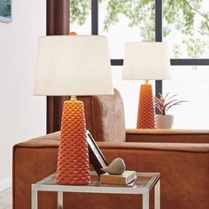 two orange vases sitting on top of a table in front of a brown couch