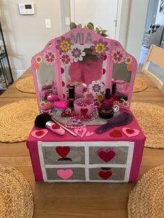 a pink vanity with flowers and hearts on it