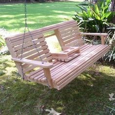 a wooden swing hanging from a tree in the grass