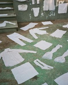 clothes are laid out on the ground in front of a wall with stairs and windows