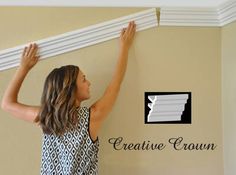 a woman is holding up the top of a white window seal on a beige wall