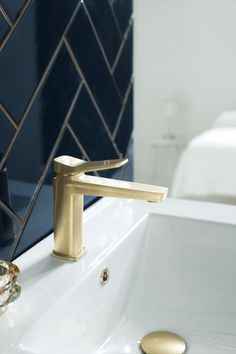 a bathroom sink with a gold faucet next to it