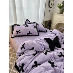 a bed covered in a purple blanket with black crosses on the comforter and pillows