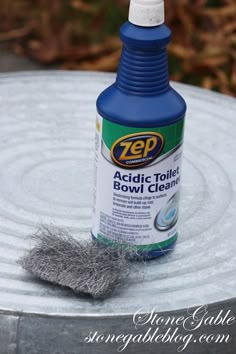 a bottle of zep toilet bowl cleaner sitting on top of a metal table next to a brush