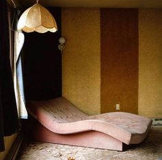 a pink couch sitting in front of a window next to a wall with stripes on it