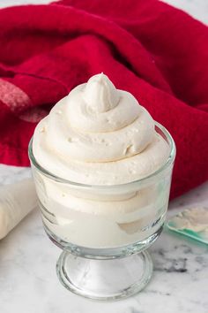 a glass bowl filled with whipped cream on top of a counter next to a red towel