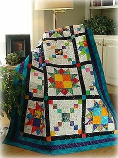 a quilted blanket sitting on top of a wooden floor next to a table lamp