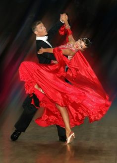 two people dressed in red dancing on a dance floor