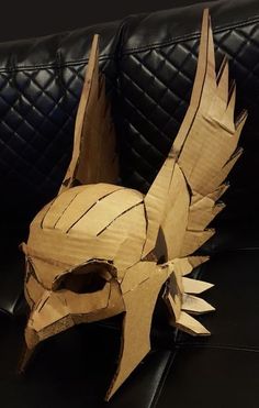 a wooden mask made to look like a dragon's head on a black leather couch