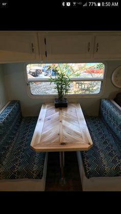 a table and bench in a small room with blue cushions on either side of the window