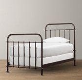 a metal bed frame with white sheets and pillows