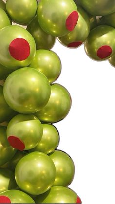 green balloons with red dots are hanging from the ceiling in front of a white background