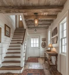 a hallway with wooden floors and stairs leading up to the second floor, along with pictures on the wall