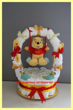 a winnie the pooh diaper cake with a teddy bear sitting on top of it