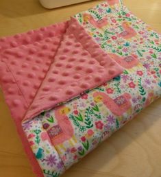 two pieces of pink and green fabric sitting on top of a wooden table next to a sewing machine