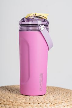 a pink insulated cup sitting on top of a wicker table