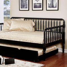 a black daybed sitting on top of a hard wood floor next to two framed pictures