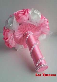 a bridal bouquet in pink and white with pearls on the end is sitting on a table