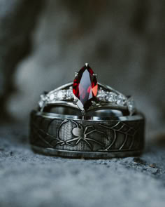 A matching set of gothic or halloween wedding rings from Staghead Designs sits on a gray statue. On top is the "Persephone" 14K white gold engagement ring with a marquise cut garnet, claw prongs, and diamond accents. Below sits the "Legacy" titanium wedding band with engraved spider and spider webs. Colour Scheme Ideas, Red Wedding Ideas, Wedding Colors Red, Garnet Engagement Ring, Matching Wedding Rings, Staghead Designs, 14k Gold Engagement Ring