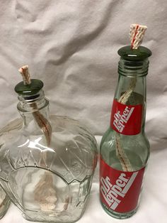 two empty glass bottles with rope sticking out of the top, and one empty coca - cola bottle next to it