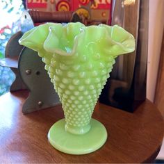 a green vase sitting on top of a wooden table