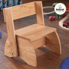 a wooden chair sitting on top of a hard wood floor next to toy cars and toys