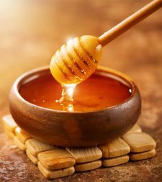 a wooden bowl filled with honey sitting on top of some small pieces of wood and the words, what is manuka honey good for?