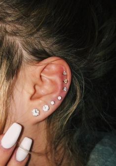 a close up of a person's ear with some piercings on top of it