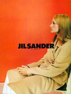 a woman sitting on top of a chair in front of a red wall with the words jil sander