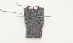 a pair of scissors is hooked up to a gray knitted mitt with red string