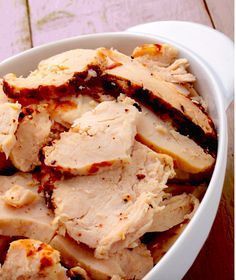 a white bowl filled with sliced meat on top of a wooden table