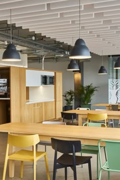 an office with tables and chairs in the center, lights hanging from the ceiling above them