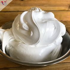 a metal bowl filled with whipped cream on top of a wooden table