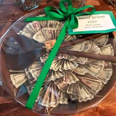 a glass platter with money in it and a green ribbon tied around the edge