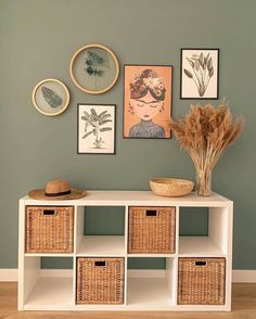 a white shelf with baskets and pictures on the wall