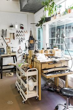 a workbench with lots of tools on it in a room filled with plants